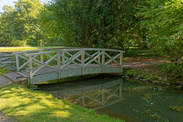 Small wooden bridge over a stream with trees in the background.