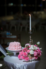 beautiful pink wedding cake. white vintage wedding cake on wooden table, outside, black and bokeh background.