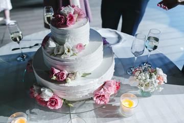 Three-level cake decorated with flowers roses on a table.