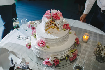 Three-level cake decorated with flowers roses on a table.
