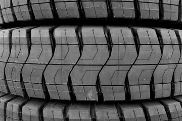 Close up side view of several giant new and unused stacked tires with unique tread patterns