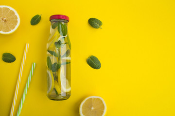 Detox water with lemon and mint in the glass bottle  on the yellow  background.Top view.Copy space.