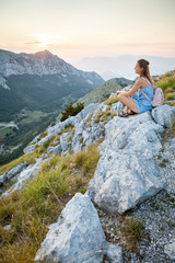 Naklejka na ściany i meble Beautiful girl tourist stands on top of a cliff and admires the beautiful landscape of the mountain range in Montenegro . Tourism, Travel and summer holiday concept