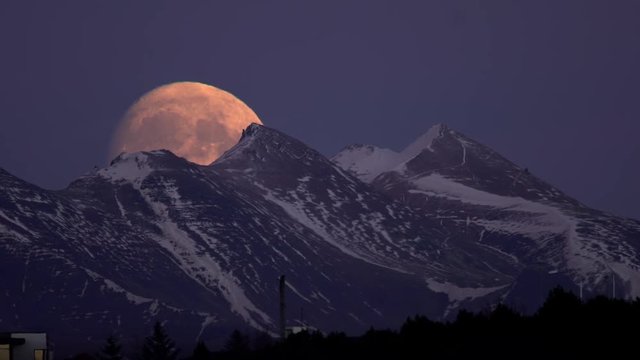 Rising supermoon cresting snowy mountain ridge, Reykjavik Iceland.mov