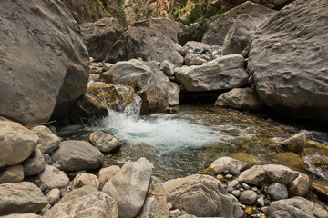 Naklejka na ściany i meble Crystal clear water of a cold mountain creek at rocky terrain of Samaria gorge, south west part of Crete island, Greece