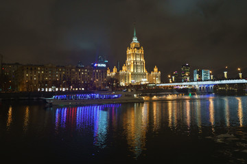 Novoarbatsky bridge and Hotel Ukraine (Radisson Royal Hotel) in bright lights and Moskva river in night winter reflections of the night Moscow.