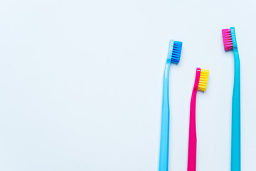 Colorful tooth brushes with bright color bristles on a light pastel blue background. Dental tools with empty space for text for  Stomatologist mockup.