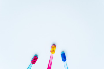 Colorful tooth brushes with bright color bristles on a light pastel blue background. Dental tools with empty space for text for  your Stomatologist mockup.