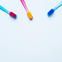 Colorful tooth brushes with bright color bristles on a light pastel blue background. Dental tools with empty space for text for  your mockup.