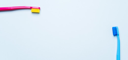 Colorful tooth brushes with bright color bristles on a light pastel blue background. Long wide banner for Stomatologist mock up with dental tools and empty space for text.