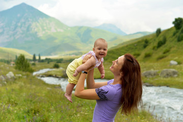 Young mother with a small child in a backpack-carrying travels in the mountains in the summer