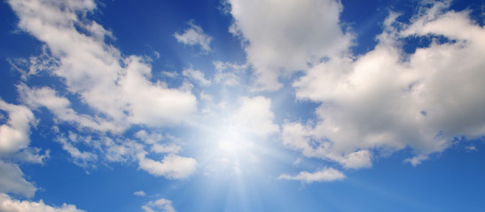 In the blue sky bright sun and light clouds. Wide photo