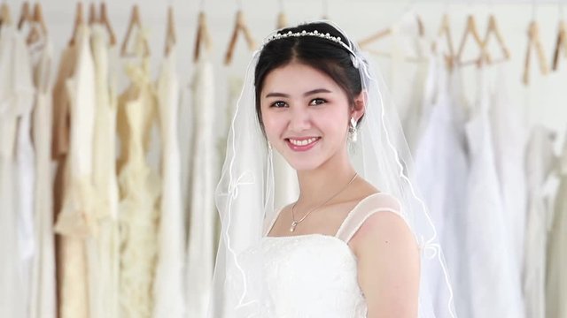 Young woman smiling and trying on wedding dress in a shop.