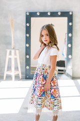 The lovely little girl posing in a beautiful blue dress.