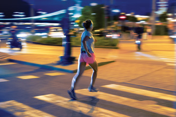 Blurred woman running in city environment at night