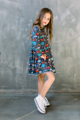 Fashion little girl child in blue dress on a grey background