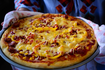 cook holds homemade organic flatbread pizza, covered with vegetables, veggies and cheese