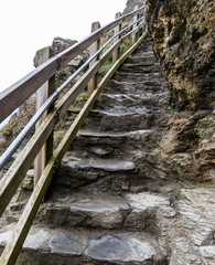 view from the bottom up, on narrow stone steps along the edge of the rock with a wooden fence