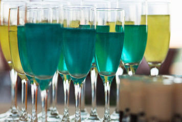 Close Up Lot of Blue Aqua and yellow green types of Champagne glass drink-beverage on  a bar.  Selective focus on the foreground glass.  Trendy black stylish  edit. Copy paste space for design concept