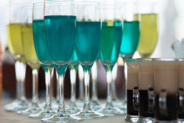 Close Up Lot of Blue Aqua and yellow green types of Champagne glass drink-beverage on  a bar.  Selective focus on the foreground glass.  Trendy black stylish  edit. Copy paste space for design concept