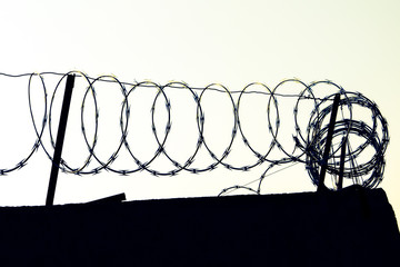 Barbed wire over the wall. Protected area surrounded with wall and barber wire. Barbed wire used to...