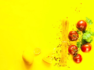 Tomatoes kumato and ingredients for cooking pasta on yellow background.