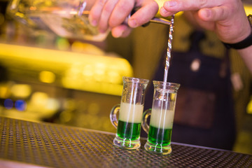 Cocktail shot green mexican with banana liqueur, lemon juice and tequila -beverage on a bar counter .  Selective focus on the foreground glass. Copy paste space for design l service barman concept