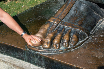 Man rubbing the foot of Ivan Mestrovic’s sculpt of Gregory of Nin (Grgur Ninski). believing that rubbing the toe while wishing will make that wish happen.