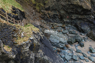 a ravine between the mountains that go to the sea; the wooden staircase with wooden fence leads down from the rocks to the water that has retreated during low tide