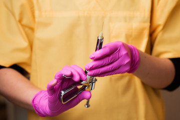 Hand of dentist in glove holding dental syringe