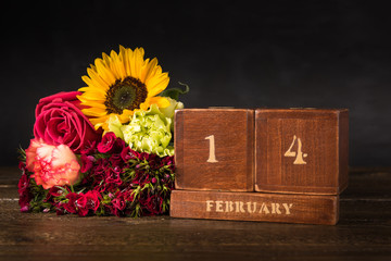 Happy Valentine's Day vintage wooden Perpetual calendar for February 14 on a black background and a bunch of red flowers
