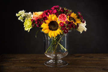 Bouquet of white yellow and red flowers in a vase on a dark background