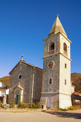 Fototapeta na wymiar Religious architecture. Village church in Mediterranean. Montenegro, Tivat. View of Catholic Church of Saint Roch in Donja Lastva village on sunny winter day