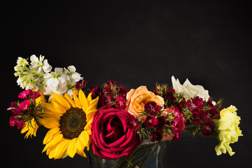 Bouquet of white yellow and red flowers in a vase on a dark background