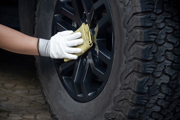 This image is a picture of wiping the car by a yellow microfiber cloth with hand wearing gloves.Car wash concept.