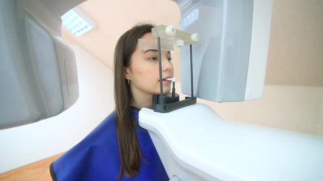 A beautiful girl is standing in a dental tomography, medical office, dentistry, patient