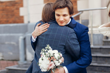 stylish groom hugging father or brother after holy matrimony in church. happy family moments....