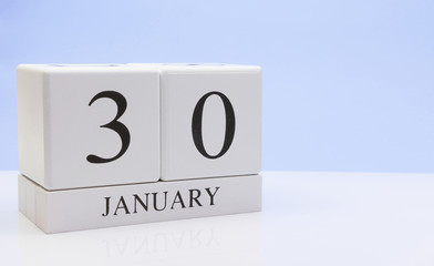 January 30st. Day 30 of month, daily calendar on white table with reflection, with light blue background. Winter time, empty space for text