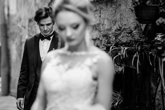 luxury wedding couple posing outdoors.  stylish bride and groom embracing in city street, heads down. romantic  sensual moment. woman and man together, black white photo