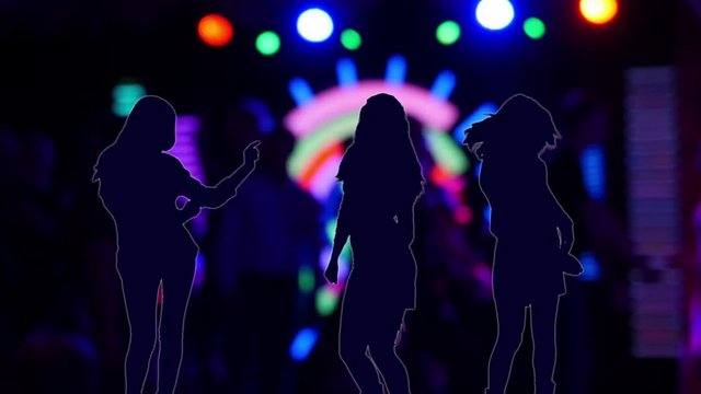 Silhouettes of young women dansing in night club