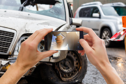 Close up hand holding smartphone and take photo of car accident