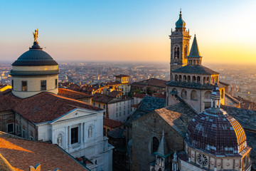 Fototapeta na wymiar Aerial view of the Basilica of Santa Maria Maggiore and the chapel Colleoni during the sunset with Po plain in background, Citta Alta, Bergamo, Italy