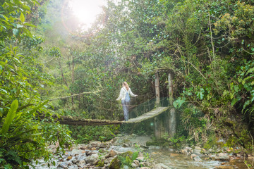Frau steht auf einer Hängebrücke im Regenwald Kolumbiens