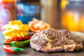 Grilled beef steak chop cutlery with fries on wooden table in fast food restaurant