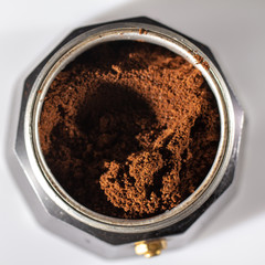 black geyser coffee maker with ground natural coffee inside on a white background