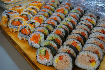 Delicious various types of Sushi rolls slices in bunch vegetarian with avocado, salmon, bacon, egg, carrot, cucumber, sesame seeds, been tuna red capsicum Japanese food traditional Asian cuisine