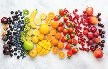 Rainbow fruits berries background on white. Top view of strawberries blueberries cherries mango...