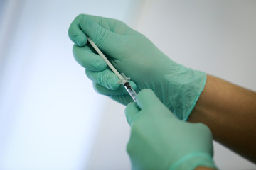 Details with the hands of a doctor extracting blood and blood plasma from a vial with a syringe