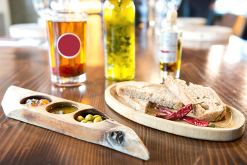 Green olives, oil and bread on wooden table at meal time