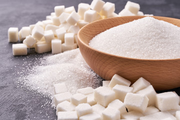 White sugar in wooden bowl, White sugar in background.